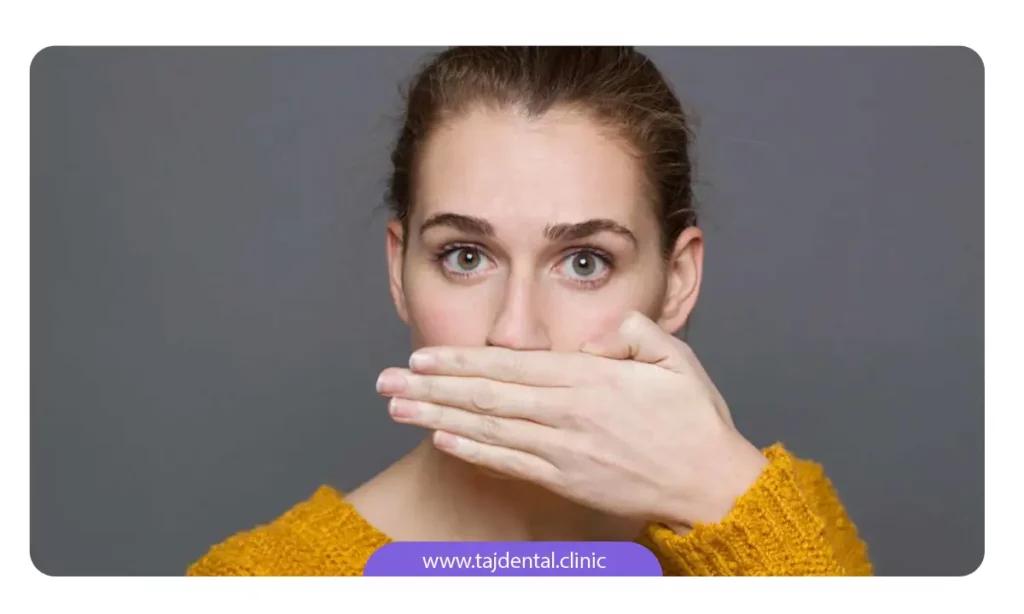 خانمی که به خاطر بوی بد دهان، جلوی دهانش را با دست گرفته